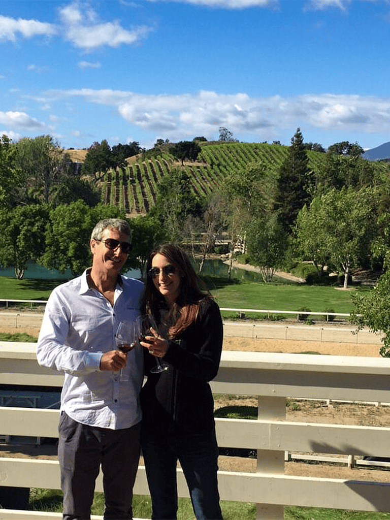 Vineyard with scenic landscape and couple enjoying wine tasting in California.