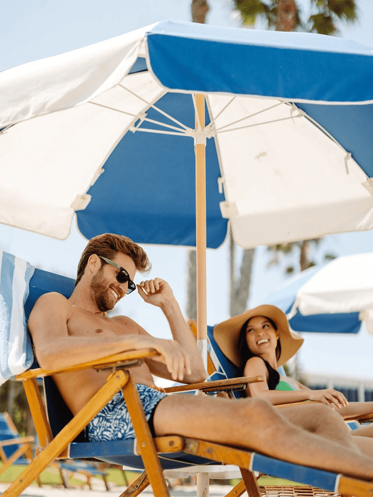 Relaxing beach scene with sunbathers under umbrellas, ideal for travel and vacation SEO.