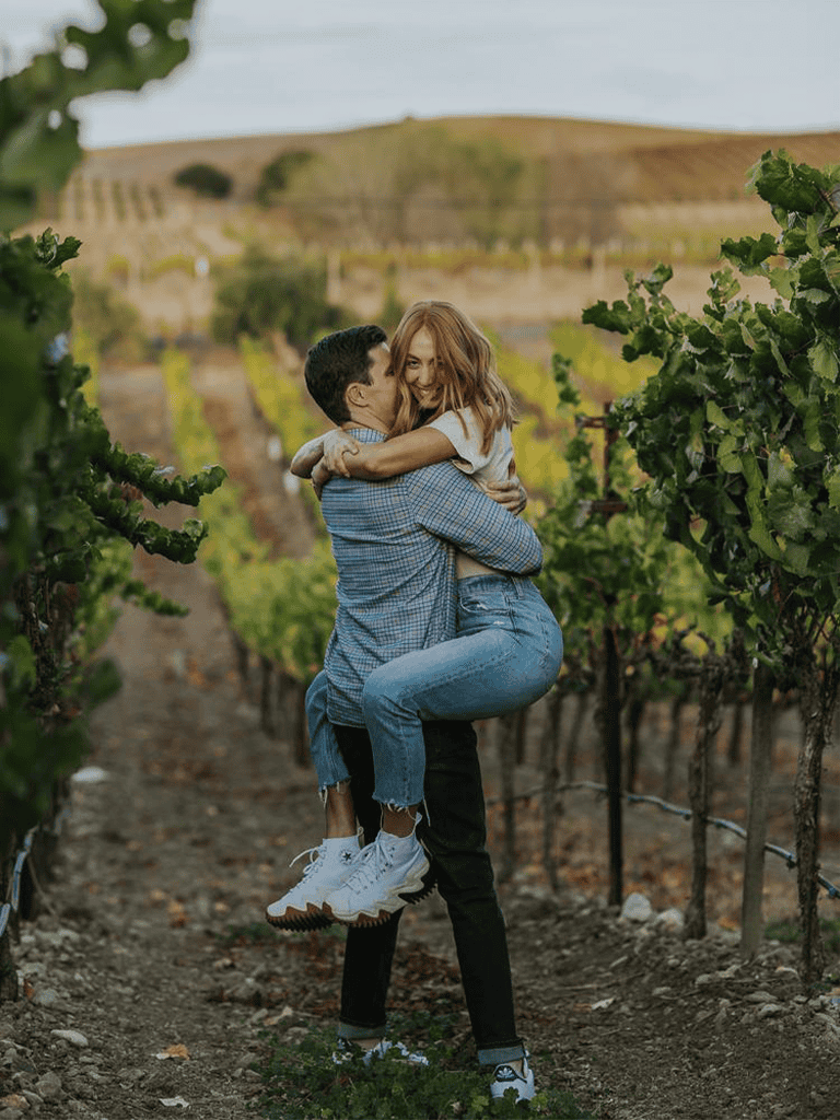 1. Happy couple embracing in vineyard during daylight, romantic outdoor scenery.
