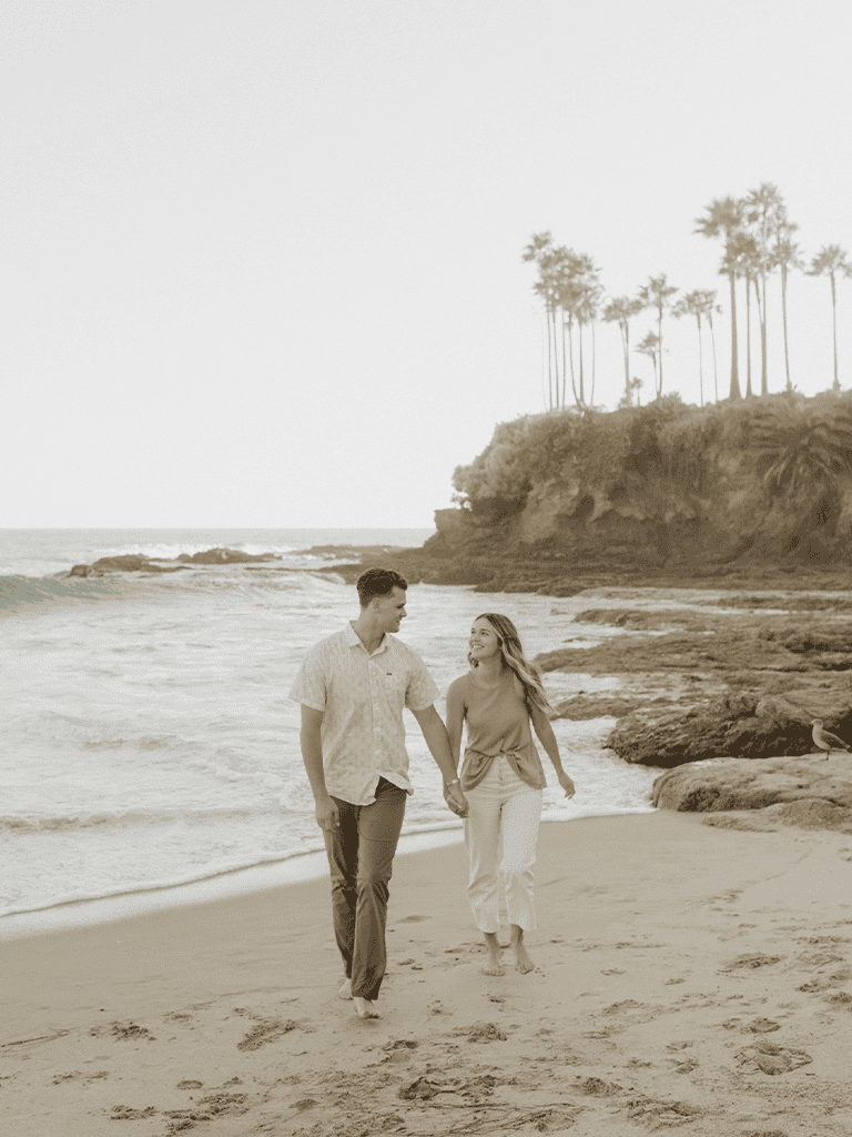 Couple walking hand in hand on the beach, exploring coastal scenery, romantic beach walk, serene ocean, palm trees, scenic seaside couple's outing.