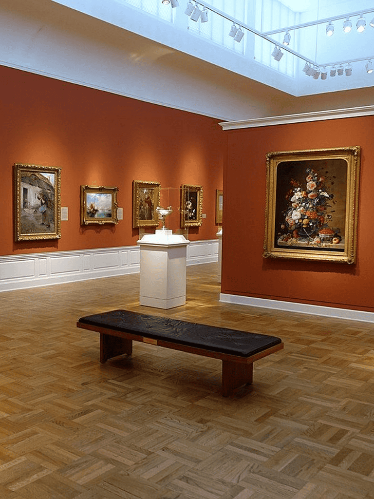 1. Art gallery interior showcasing classic paintings on warm orange walls.