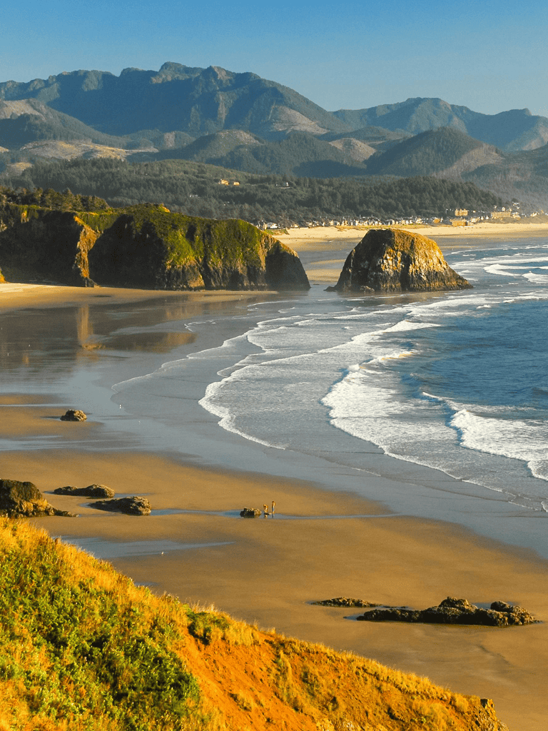 Breathtaking Oregon coast landscape with sea stacks and mountain backdrop.