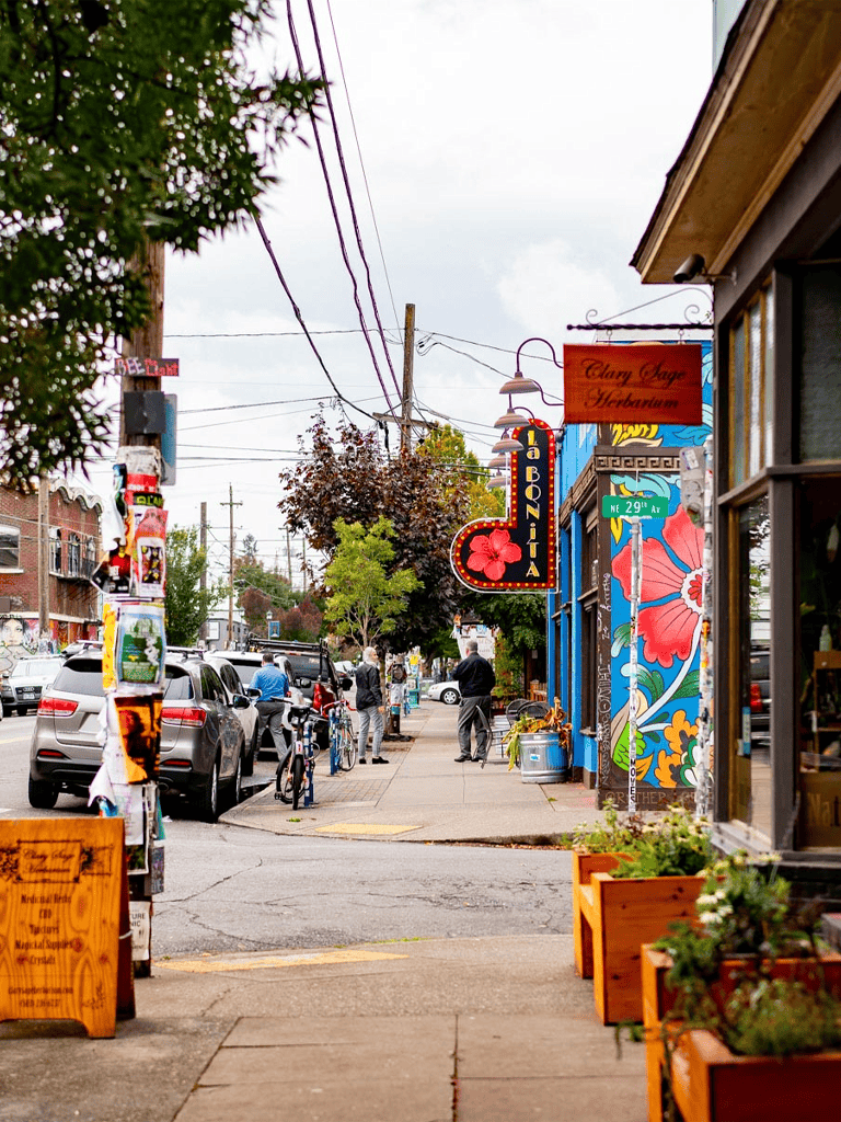 Colorful street scene with cafes, shops, and pedestrians in a vibrant urban neighborhood.