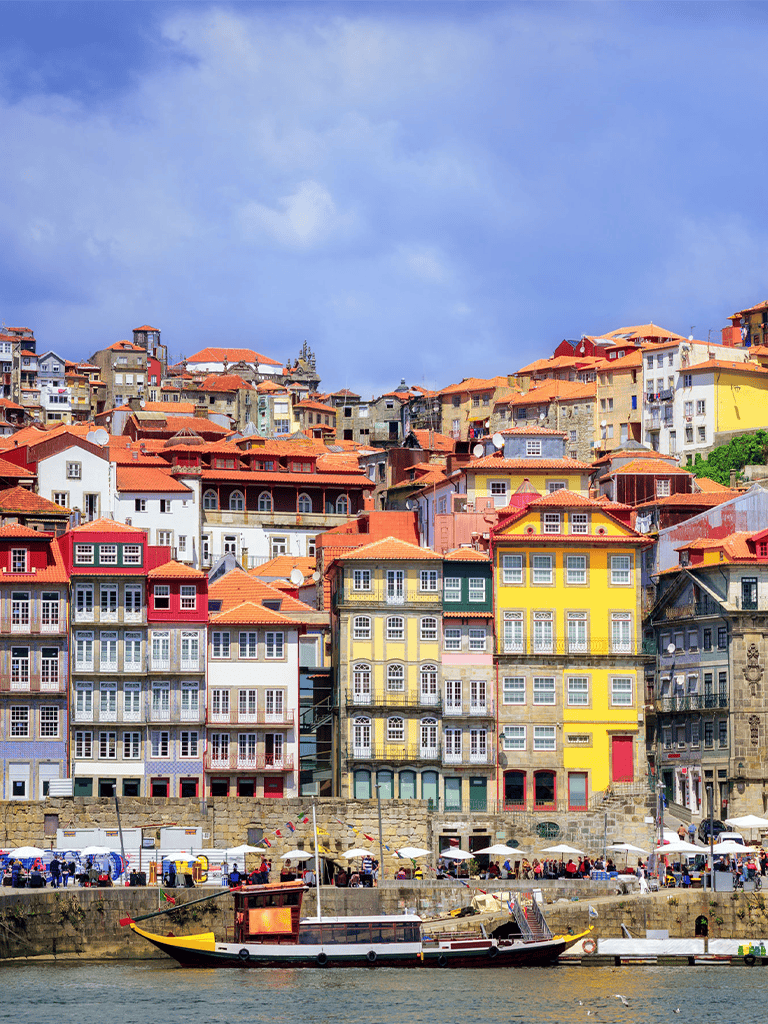 Colorful waterfront houses in Porto, Portugal, featuring traditional architecture and river views.