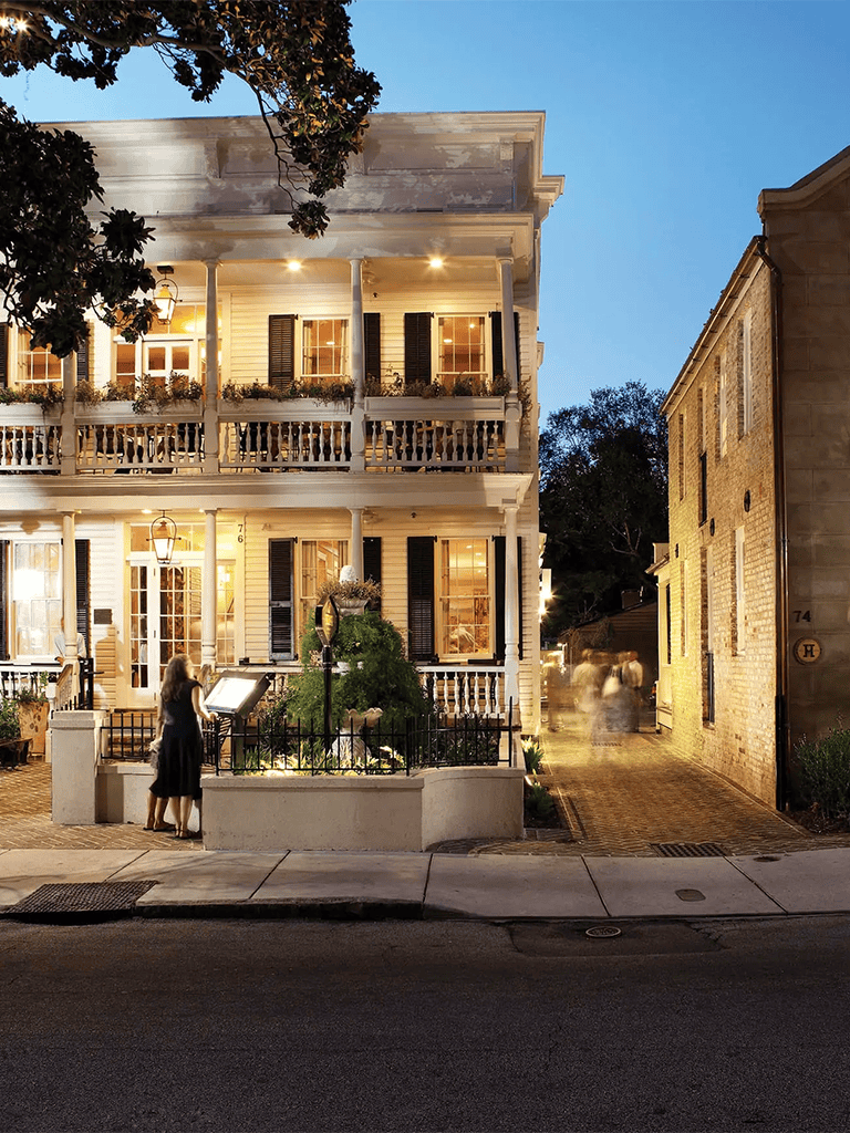Charming historic house with illuminated porch and street scene at dusk.