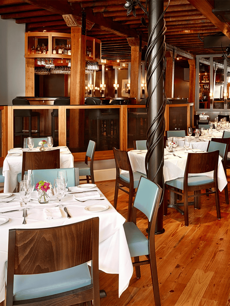 Elegant restaurant interior with wooden accents and white table settings for fine dining experiences.