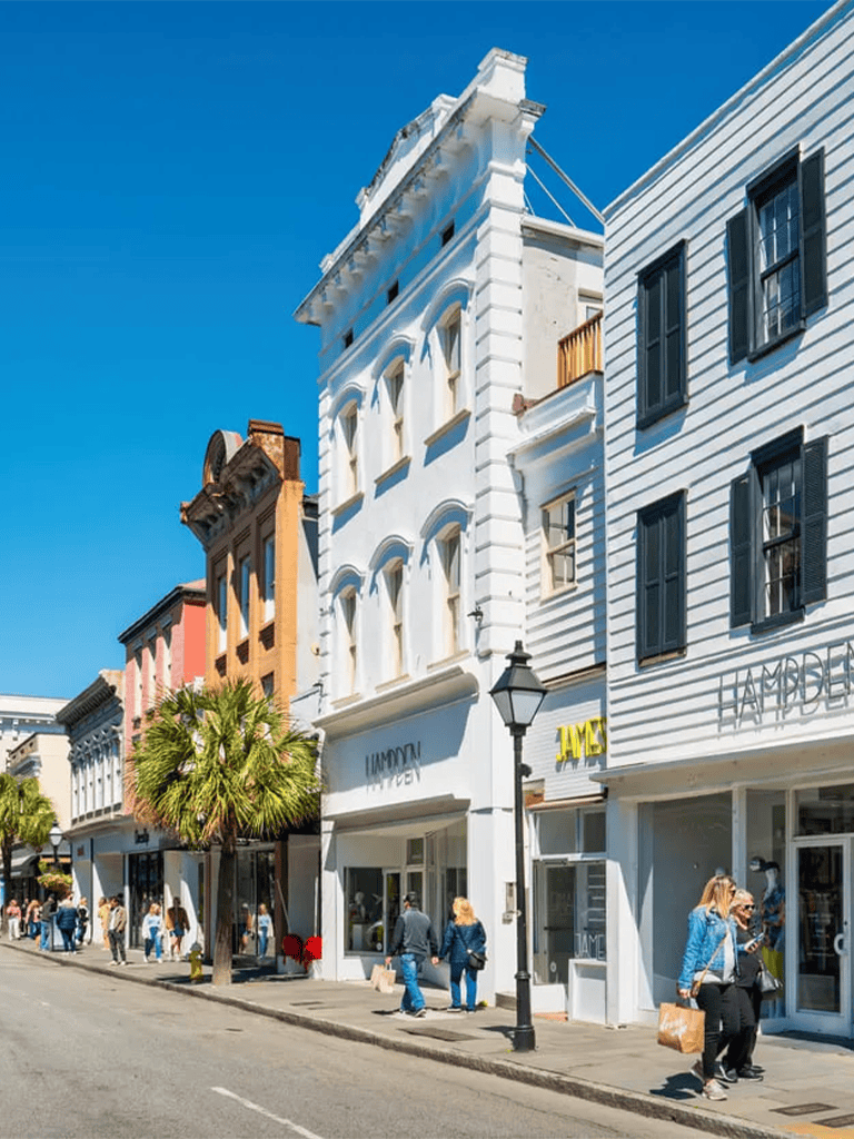 Colorful historic downtown street with shops and pedestrians under bright blue sky.