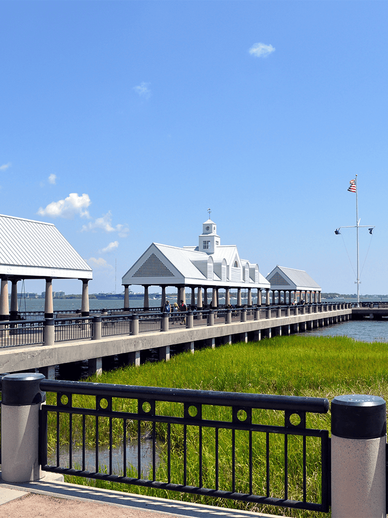 Victorian-style pier with white covered pavilions overlooking water and clear blue sky, perfect for sightseeing and leisure.