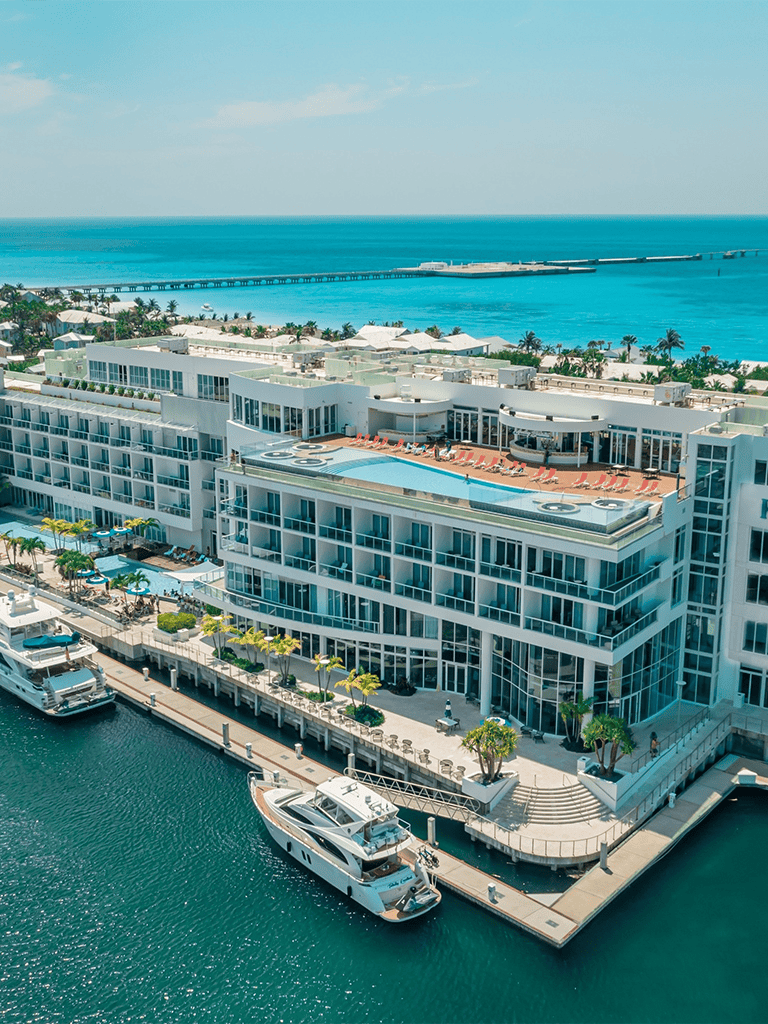 Luxurious waterfront hotel with pool and yacht dock, ocean views, and modern amenities.