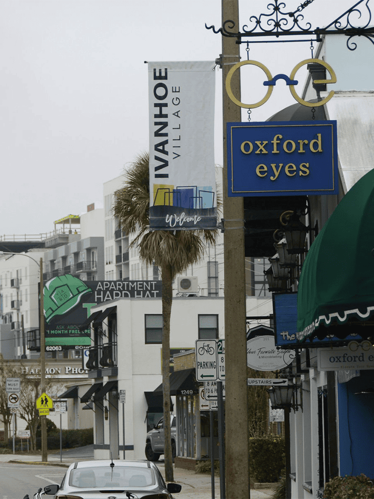 Vibrant street scene featuring Oxford Eyes sign and Ivy Anhoe Village banner in a lively neighborhood.