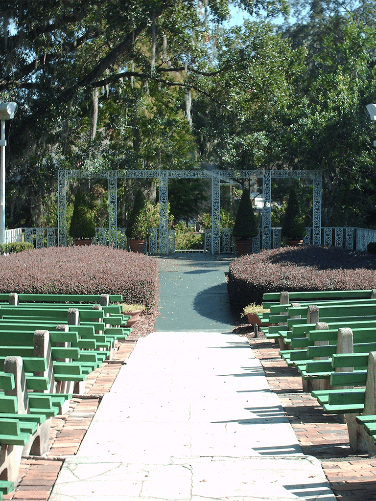 Peaceful outdoor park with benches, paved pathway, and lush greenery.