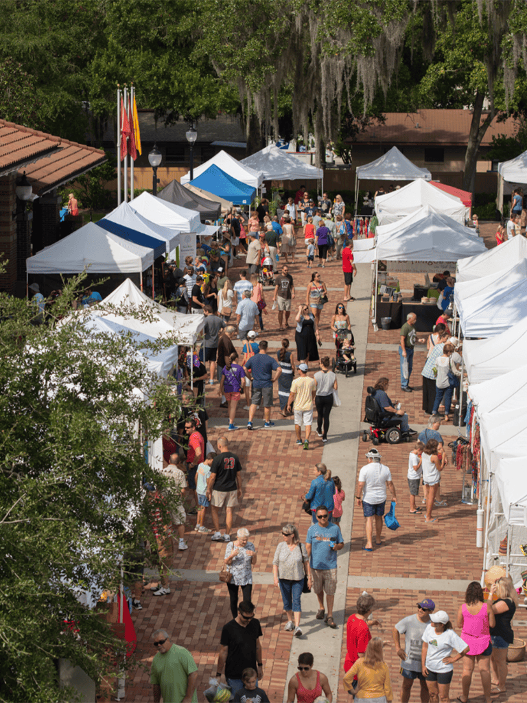 Vibrant outdoor farmers market with tents, vendors, and visitors enjoying shopping.