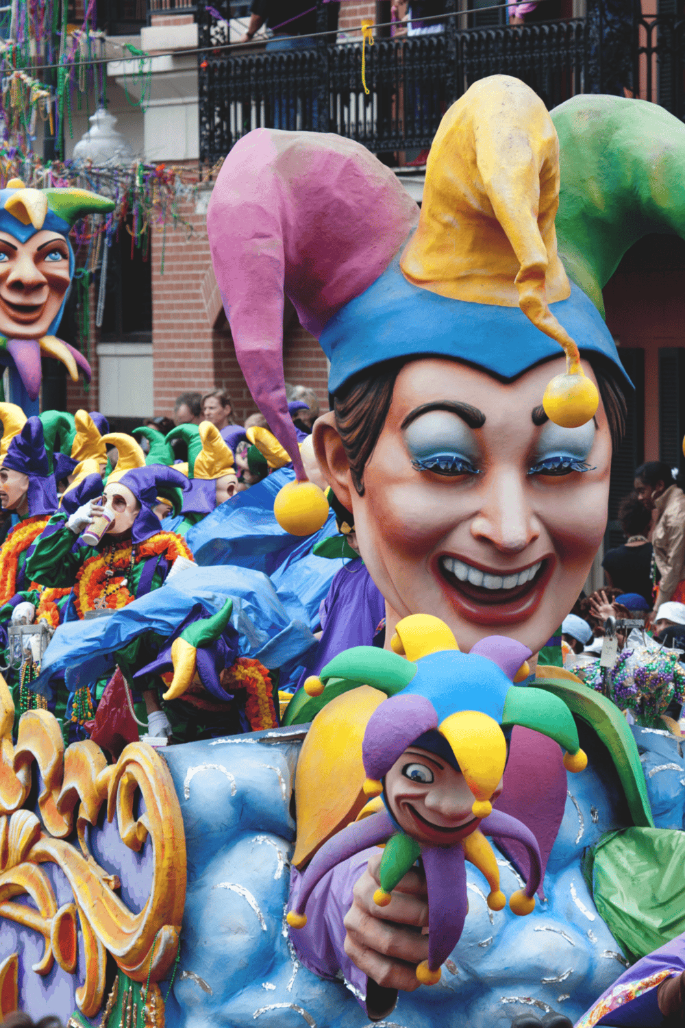 Colorful parade float with large jester face at Mardi Gras celebration, vibrant costumes, festival, parade, New Orleans, festivities, entertainment, party, cultural event, joy.