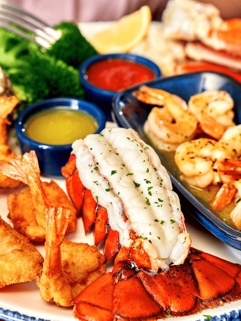 Fresh lobster seafood platter with shrimp, dipping sauces, lemon, and greens for a seafood dining experience.