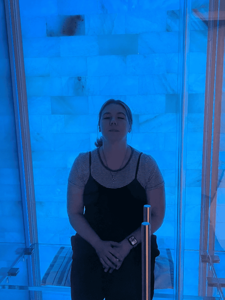 Relaxed woman in blue-lit spa or relaxation pod, enjoying tranquility and wellness atmosphere.