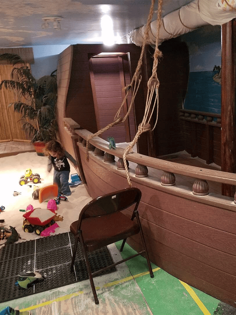 Colorful children's indoor play area with a pirate ship theme and sand flooring. Ideal for kids' entertainment and adventure.