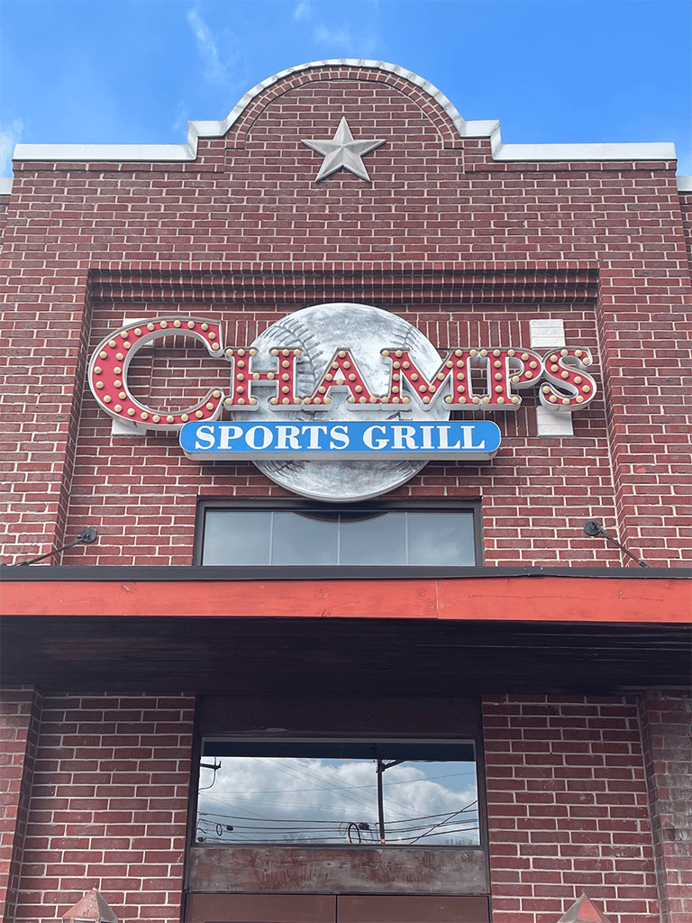 Champs Sports Grill sign on red brick building with star emblem, casual dining and sports bar atmosphere.
