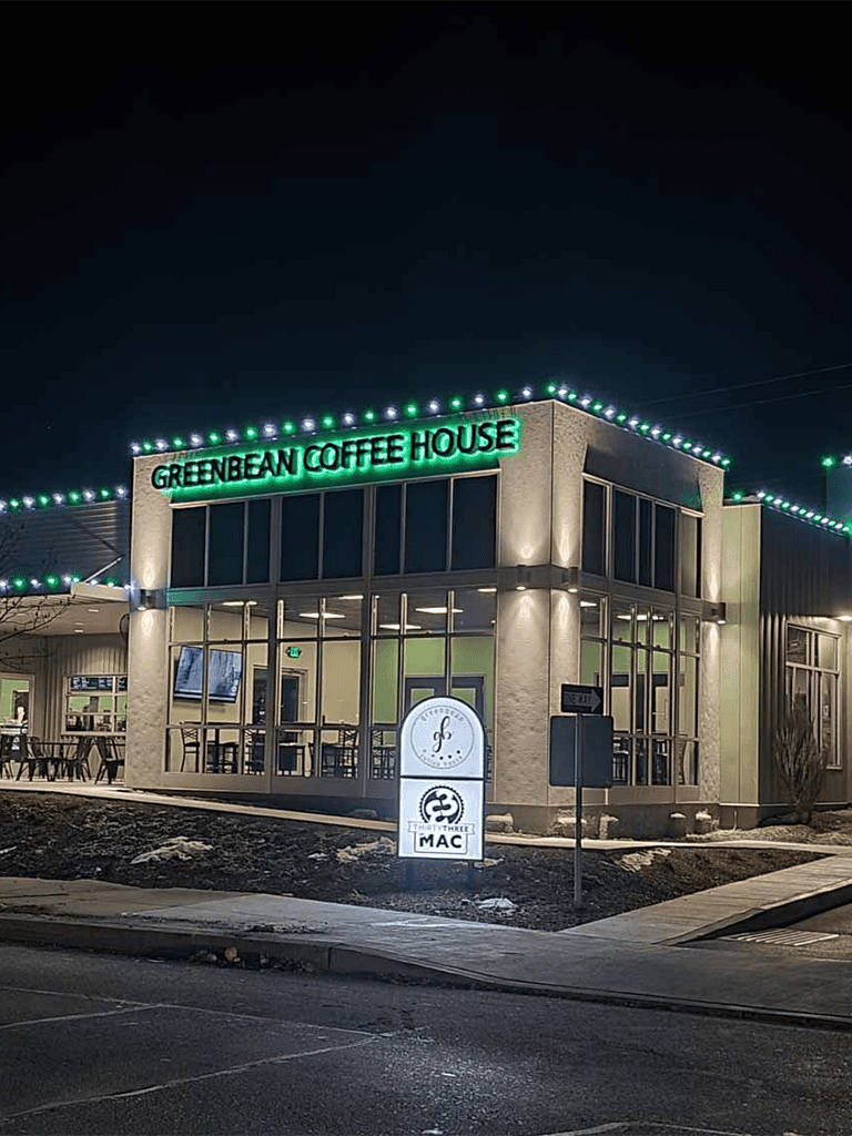 Green Bean Coffee House exterior at night with festive string lights and signage.