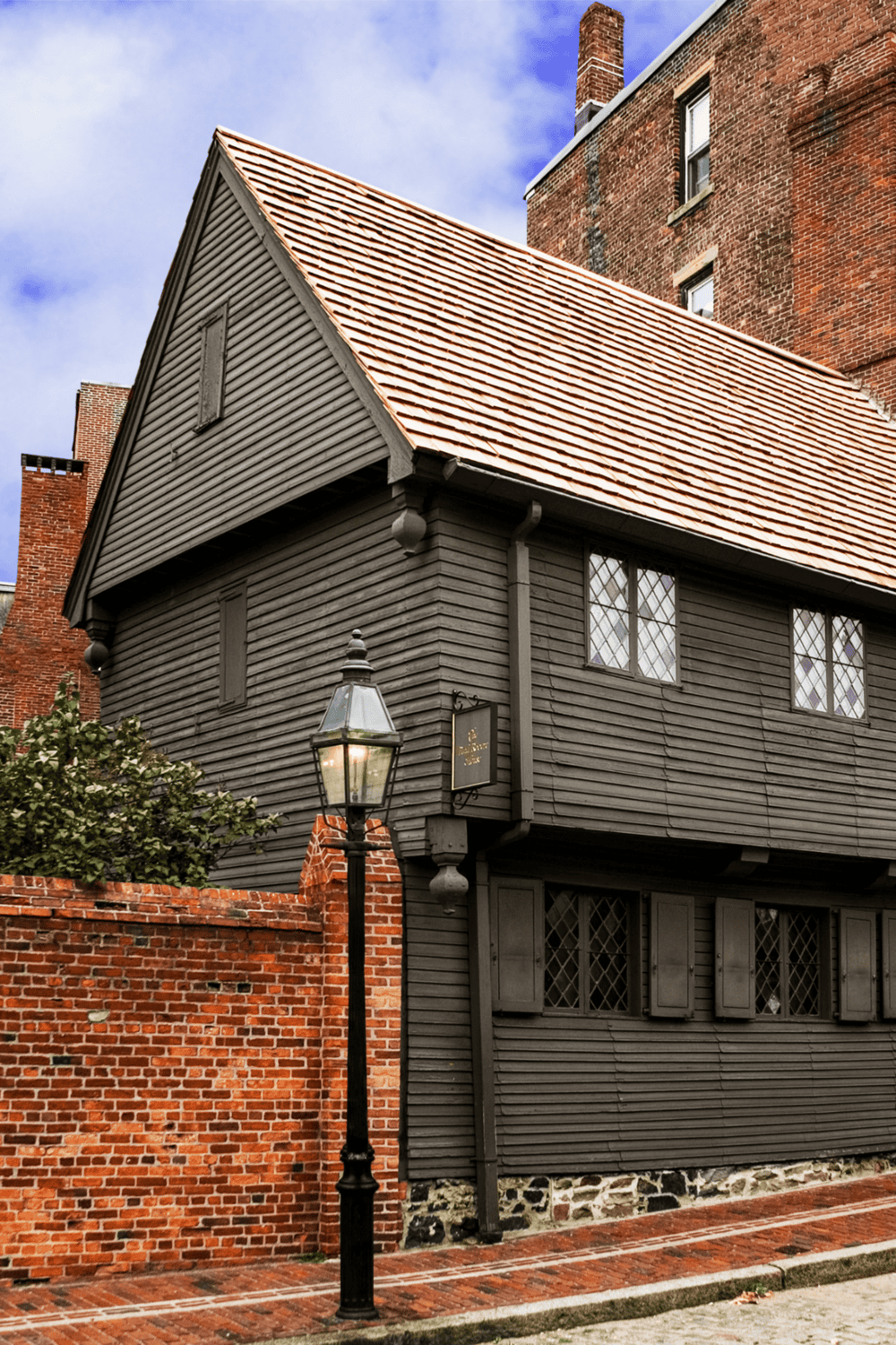 1. Old historic house with black wood siding and a red tile roof in a historic district area.