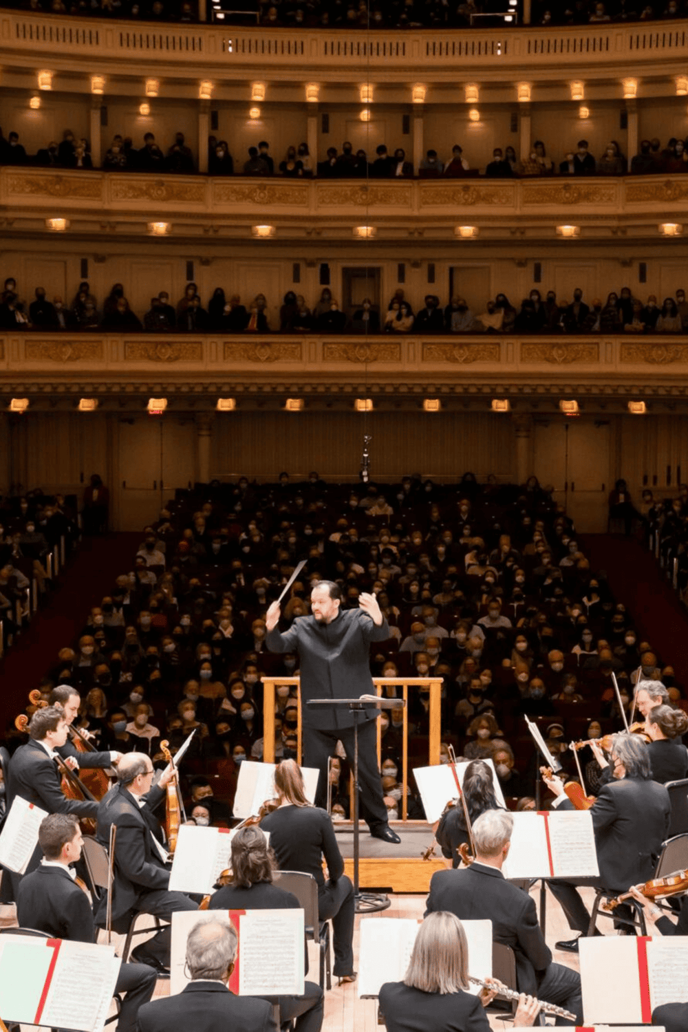 Elegant concert hall with an orchestra performing on stage.