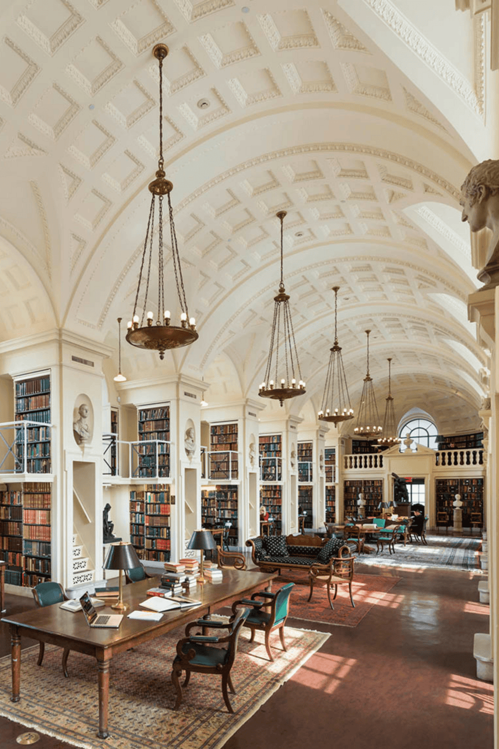 Elegant historic library interior with tall bookshelves, chandeliers, and cozy reading areas.