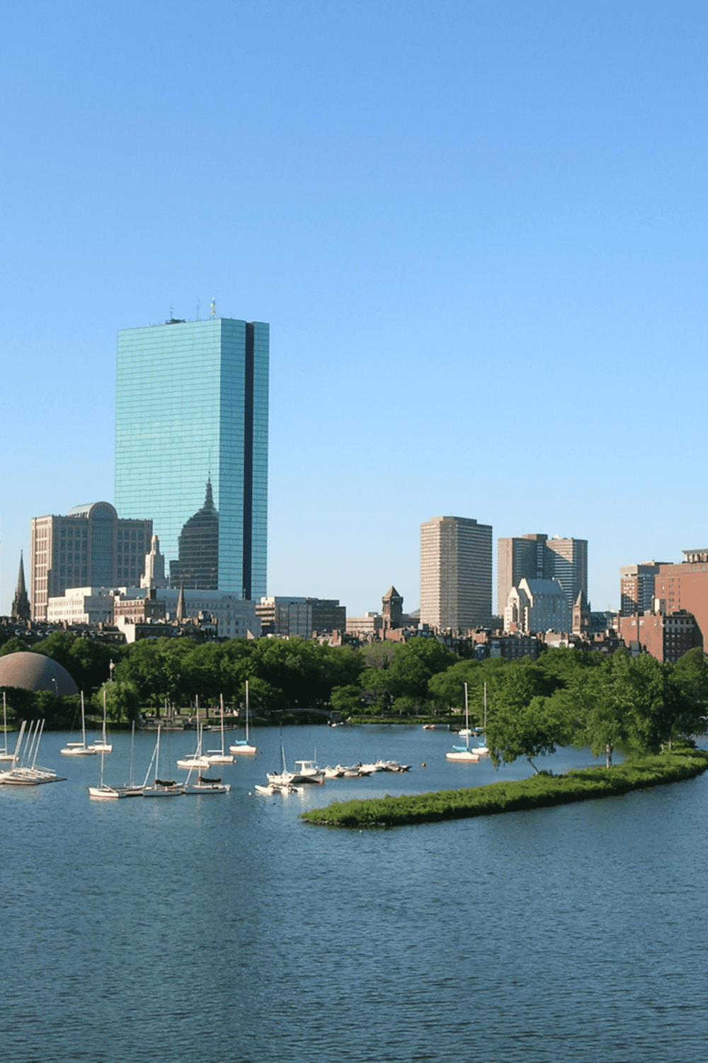 Relaxing Boston skyline view with boats on Charles River and modern high-rise buildings.
