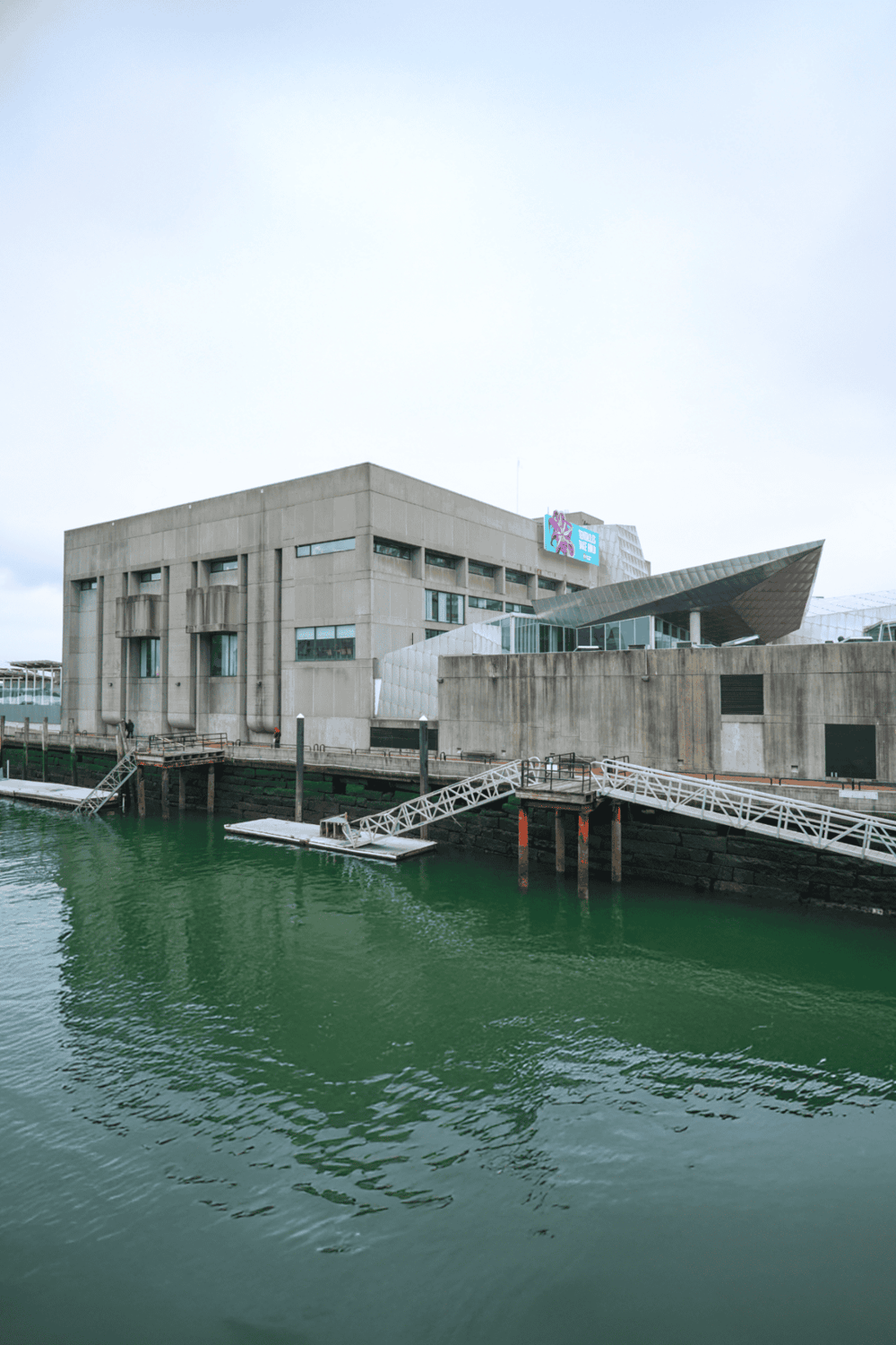 Modern waterfront building with concrete facade and unique architectural elements.