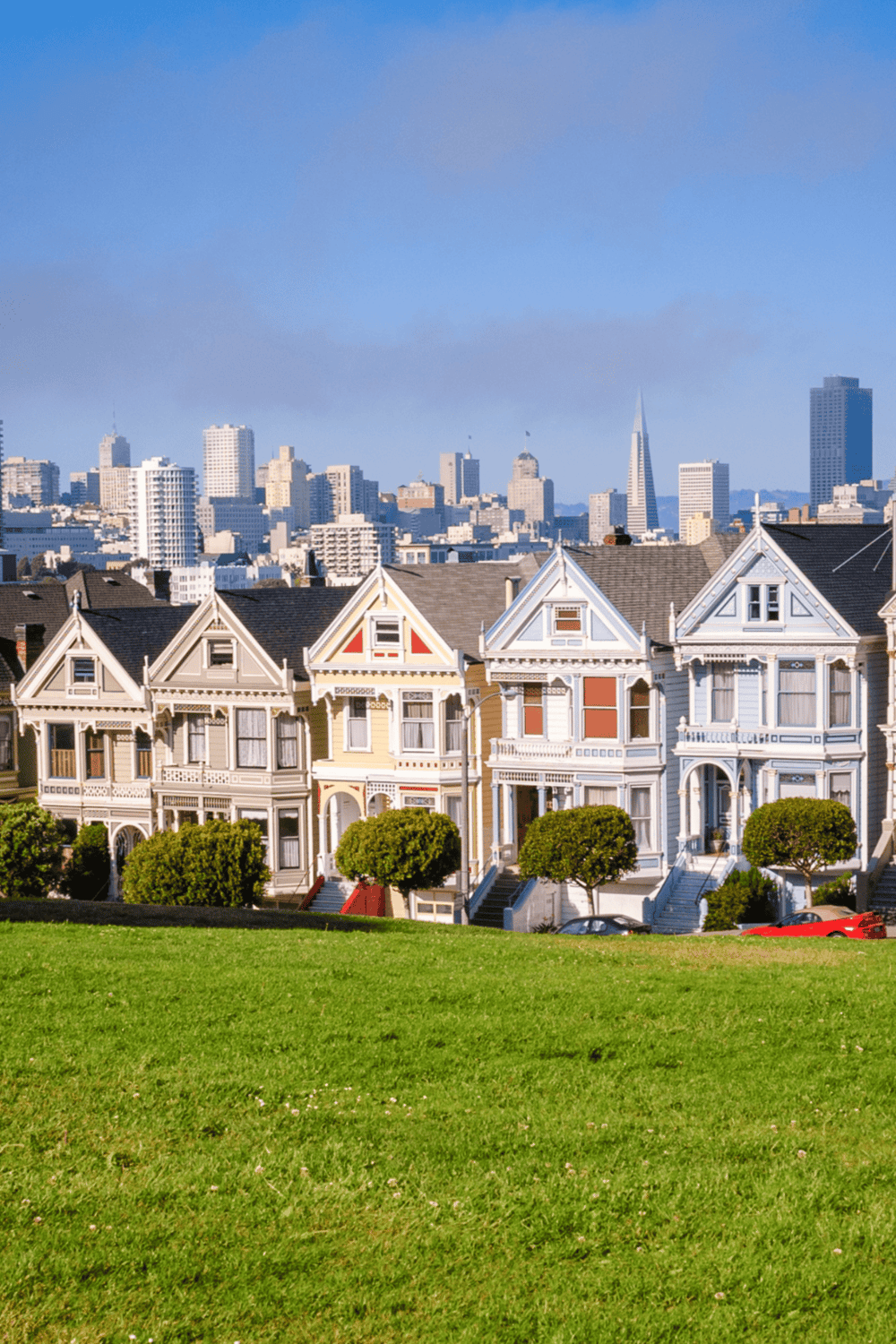 Colorful Victorian houses with San Francisco skyline in background, panoramic city view.