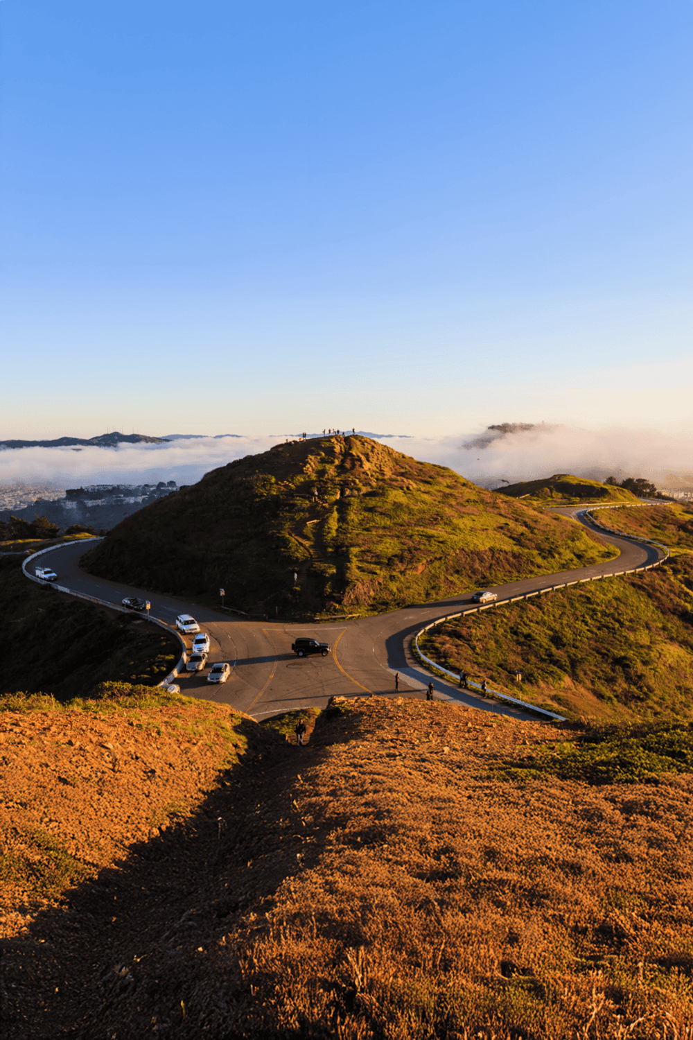 Breathtaking view of a winding mountain road with scenic hills and fog in the background, ideal for navigation and adventure.
