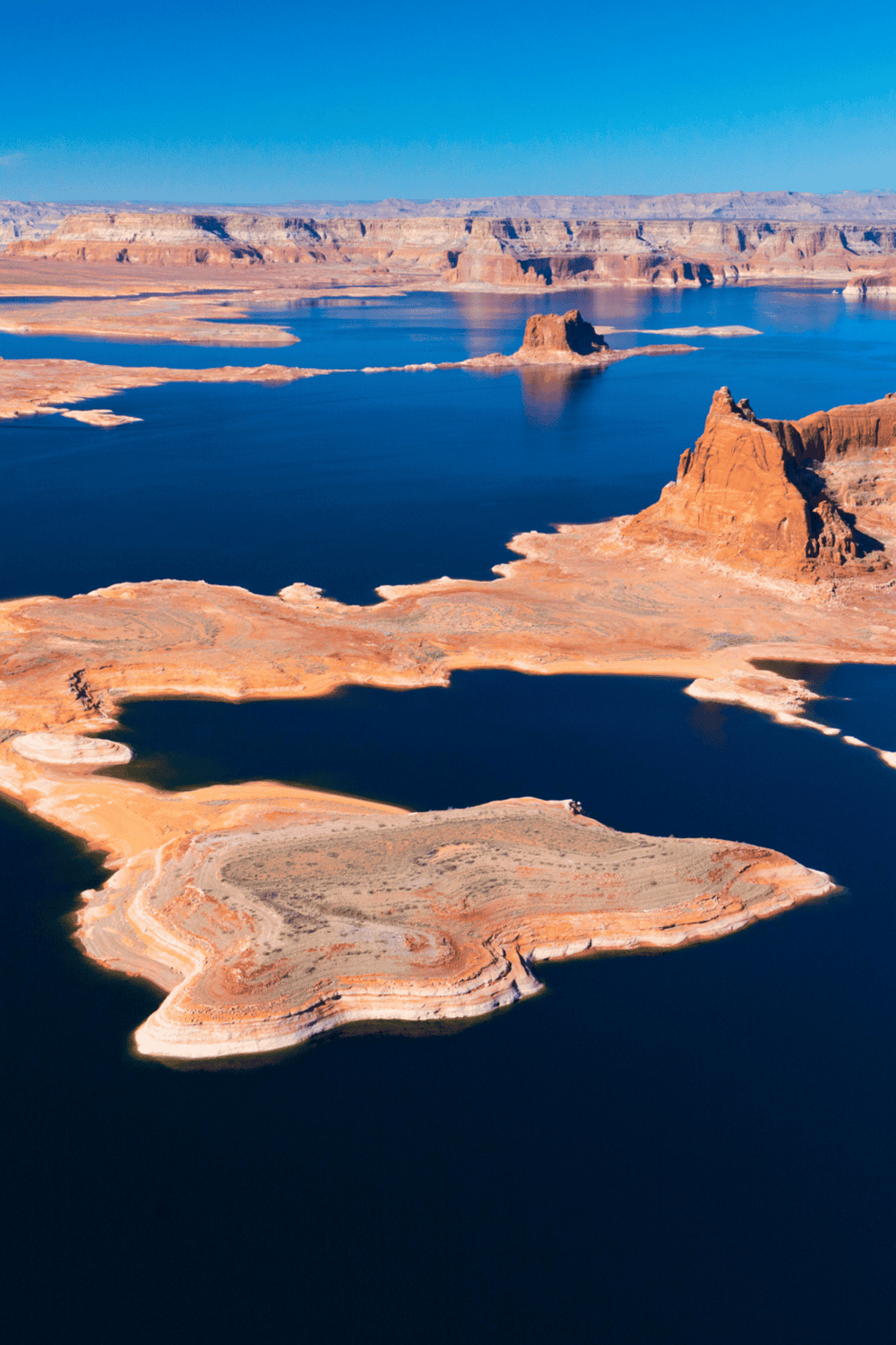 Stunning aerial view of Lake Powell with colorful rock formations and clear blue water in the Grand Canyon region.