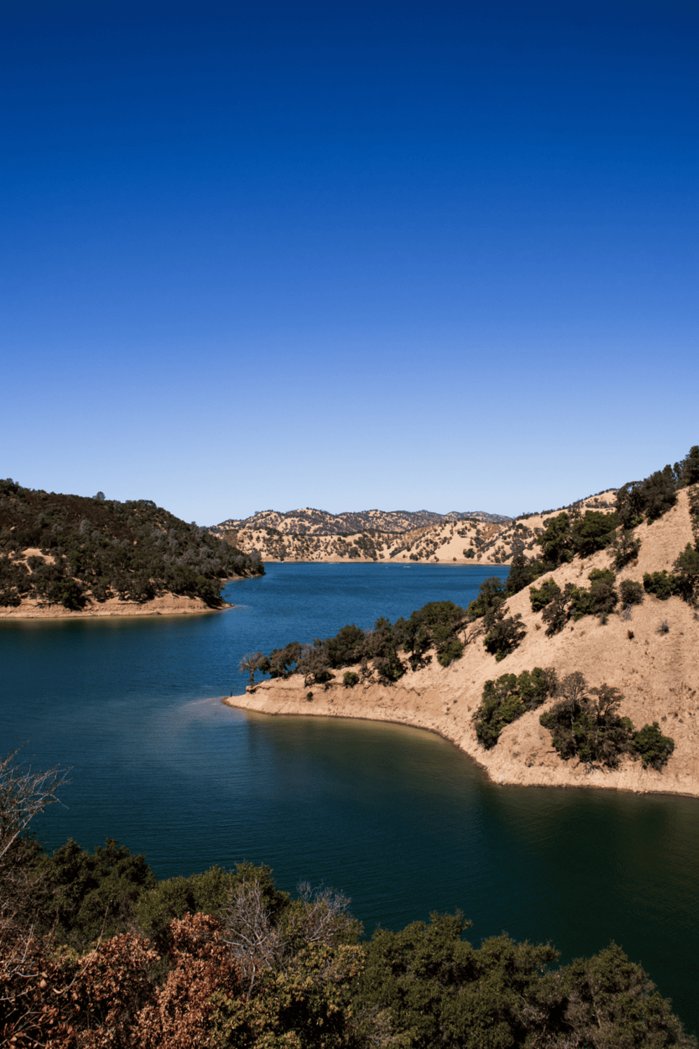 Tranquil lake surrounded by rolling hills and lush green trees, perfect for outdoor adventures and scenic exploration.