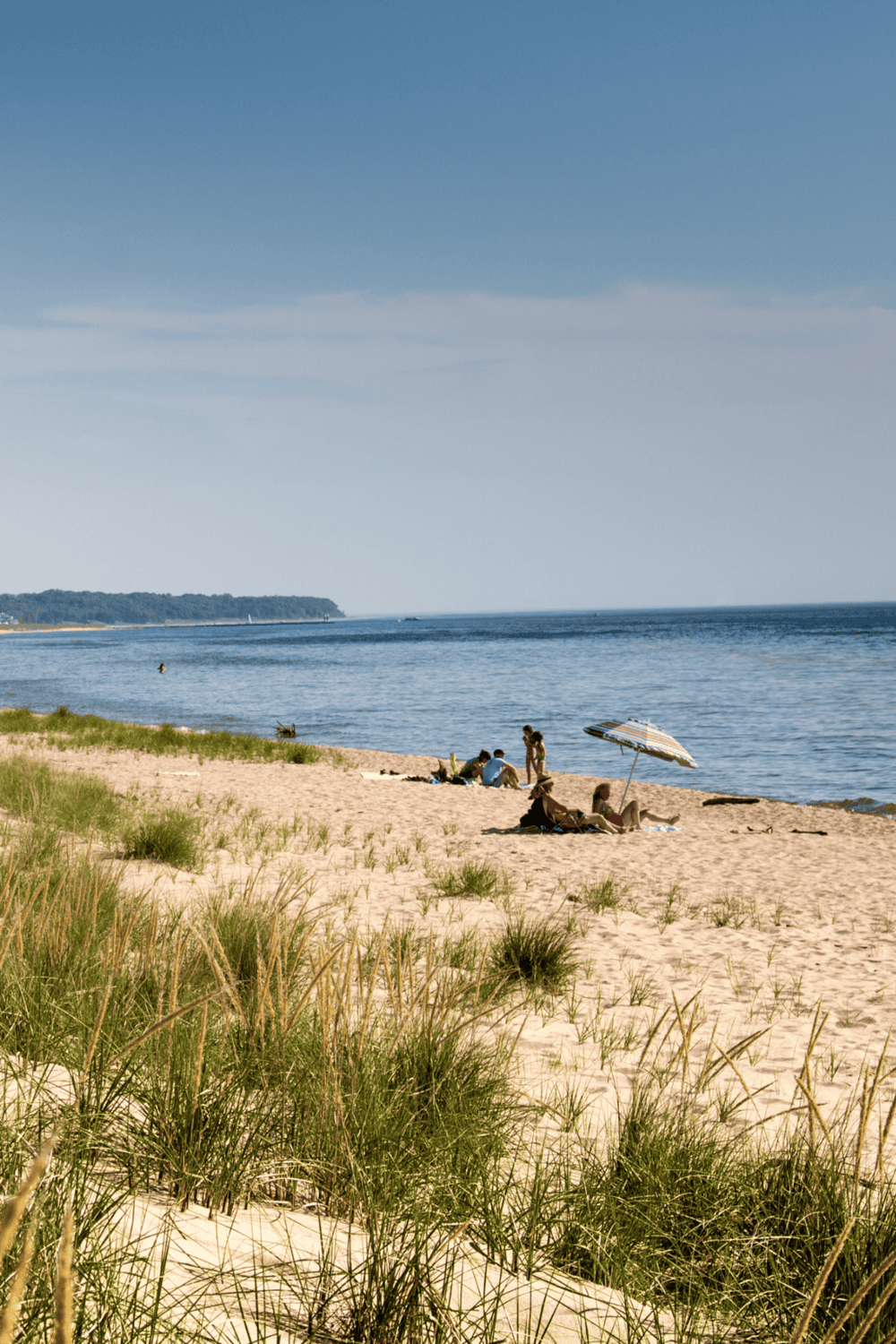 1. Beach with sand dunes, ocean, and people relaxing under umbrellas.