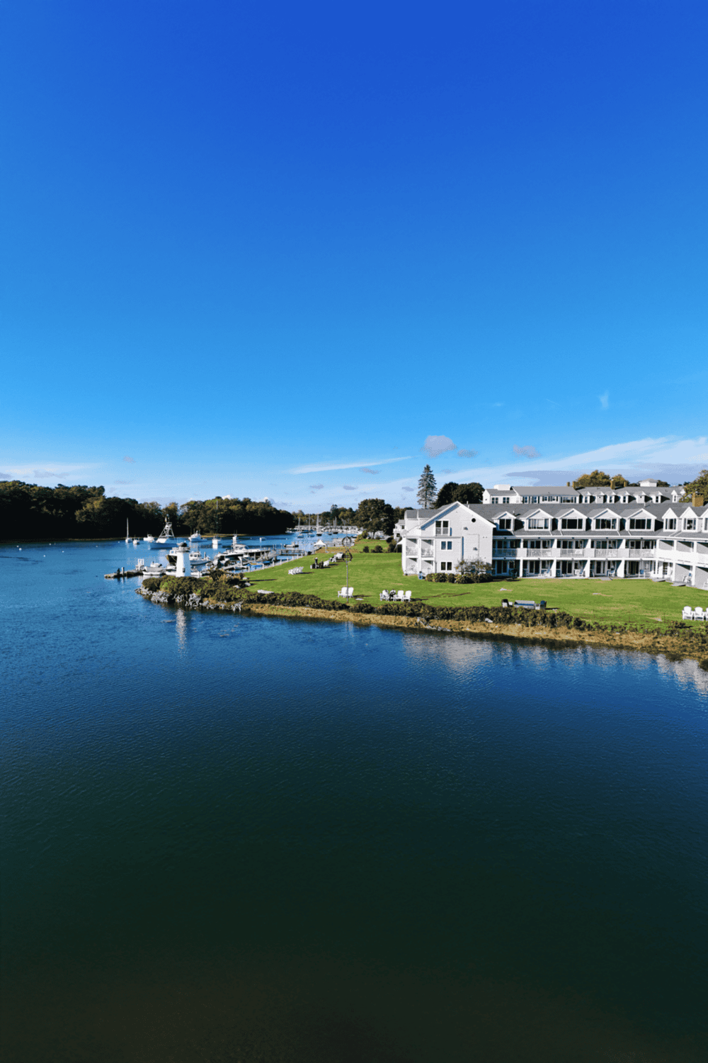 Boating marina with white buildings and lush green lawns under a clear blue sky.