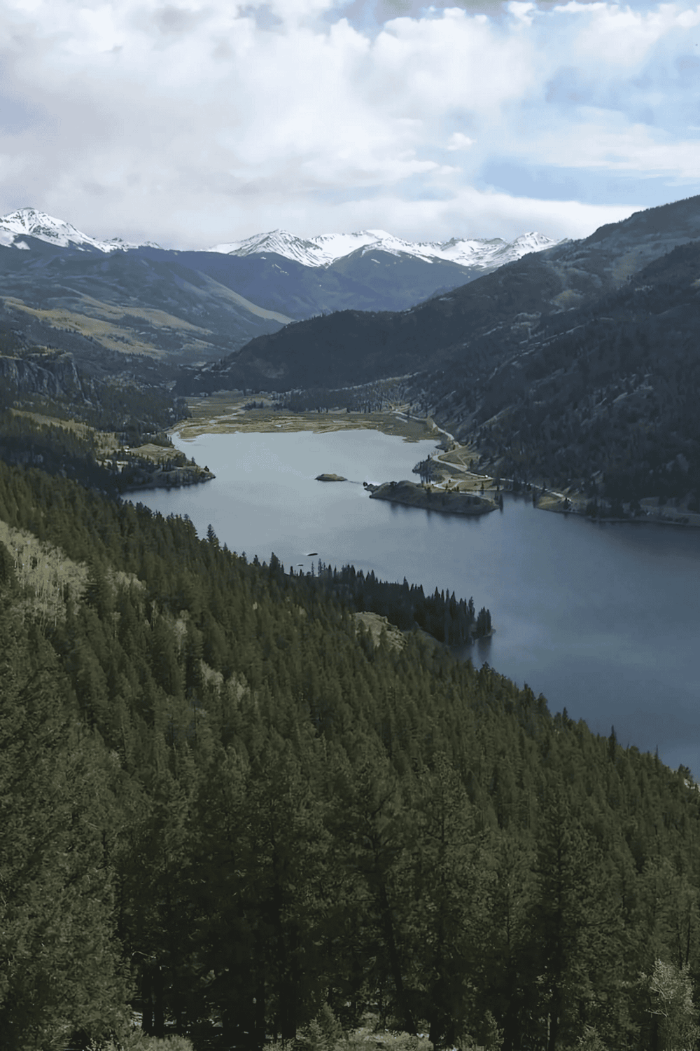 Majestic mountain lake landscape with snow-capped peaks and dense green forests, ideal for outdoor adventure and scenic exploration.