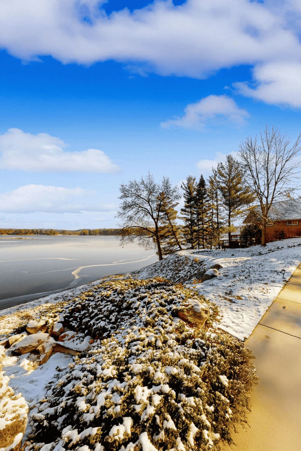 Snow-covered lakeside with trees and a pathway, capturing scenic winter travel views for QuestForDirections.
