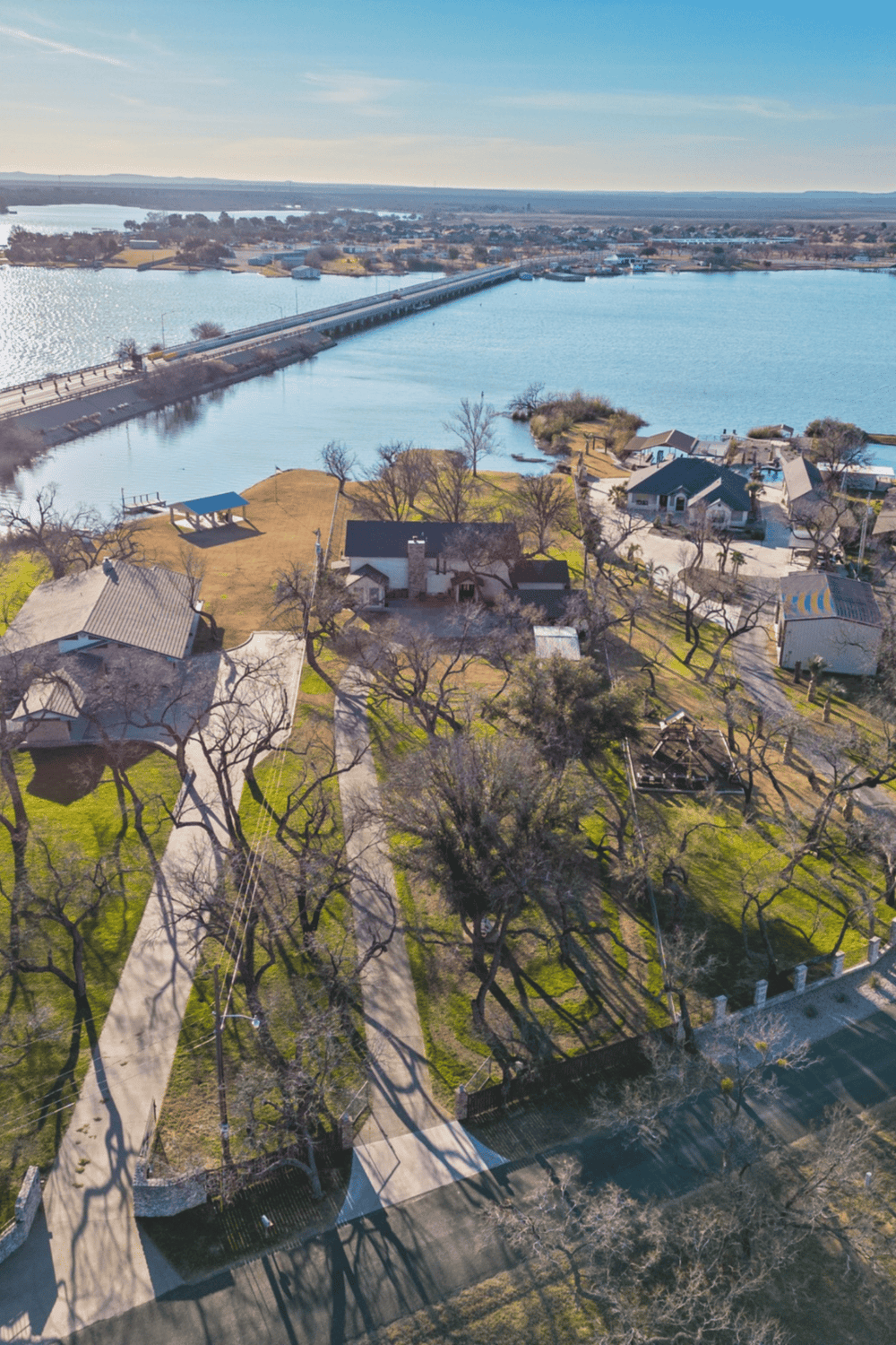 Aerial view of lakeside homes and park with bridge, scenic neighborhood in Quest for Directions.