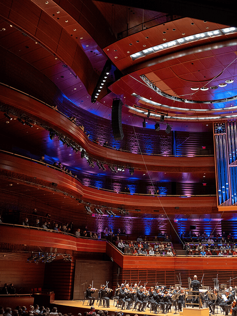 Grand concert hall interior with orchestra and audience seating for live classical music performances.