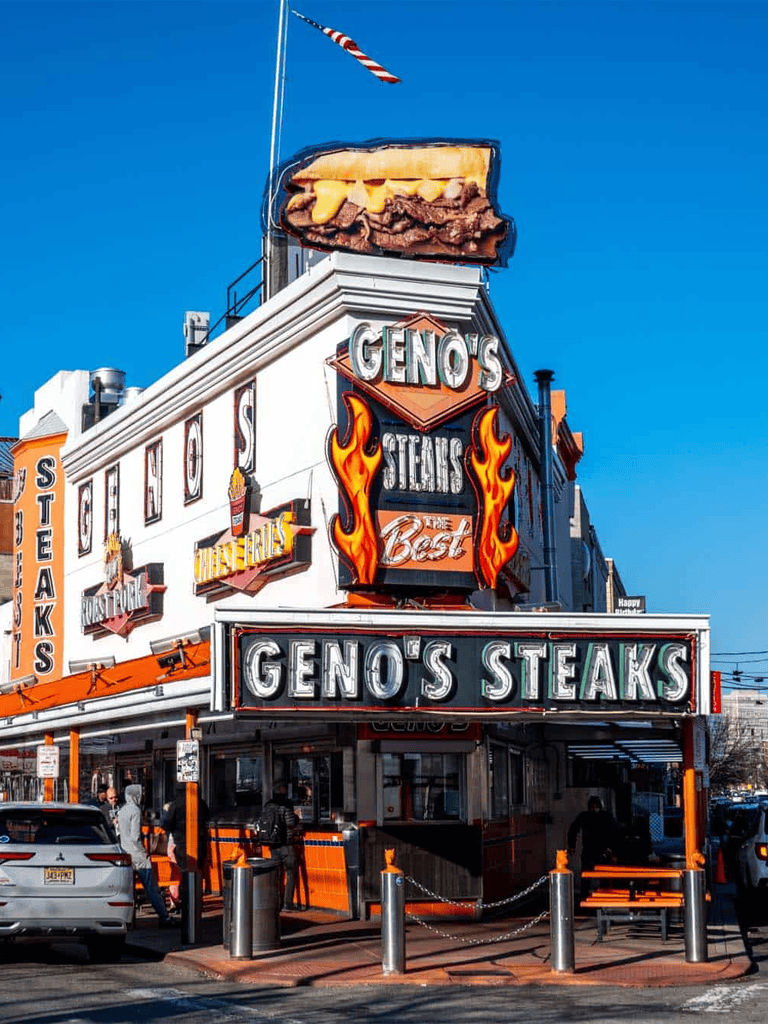 Geno's Steaks restaurant exterior with neon signs in Philadelphia, famous for cheesesteaks and American cuisine.