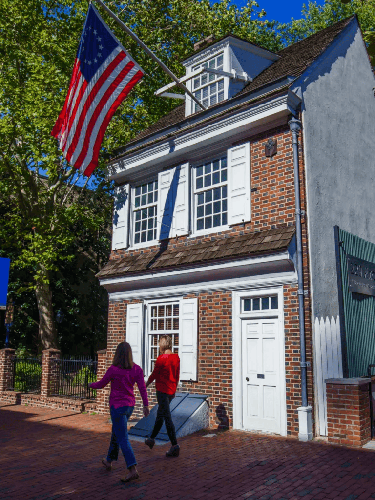American flag on historic building with couple walking by in neighborhood, questfordirections, local history, American heritage, cultural landmarks.