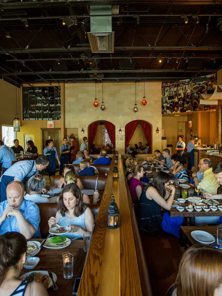 Quiet bustling restaurant interior with diverse diners enjoying meals, warm lighting, and cozy decor—ideal for dining out.