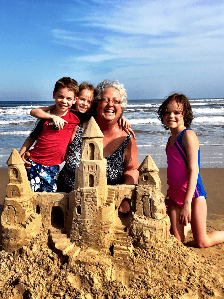 Colorful sandcastle on beach with smiling family and ocean backdrop, ideal for surf and travelSEO target.