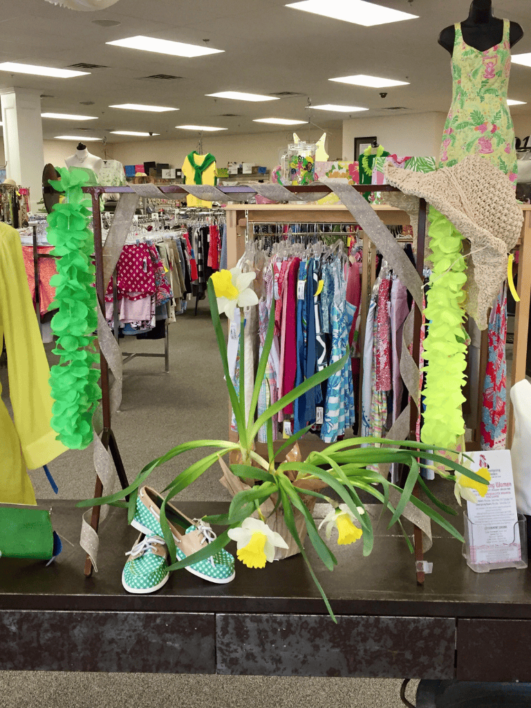 Colorful children's clothing and accessories display at QuestForDirections thrift store with spring-themed decor.