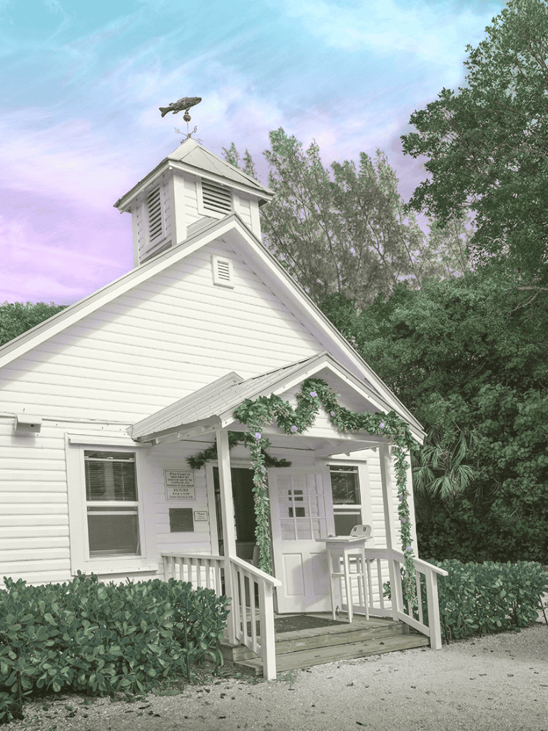 Charming white church with steeple and greenery, perfect for community gatherings and services.