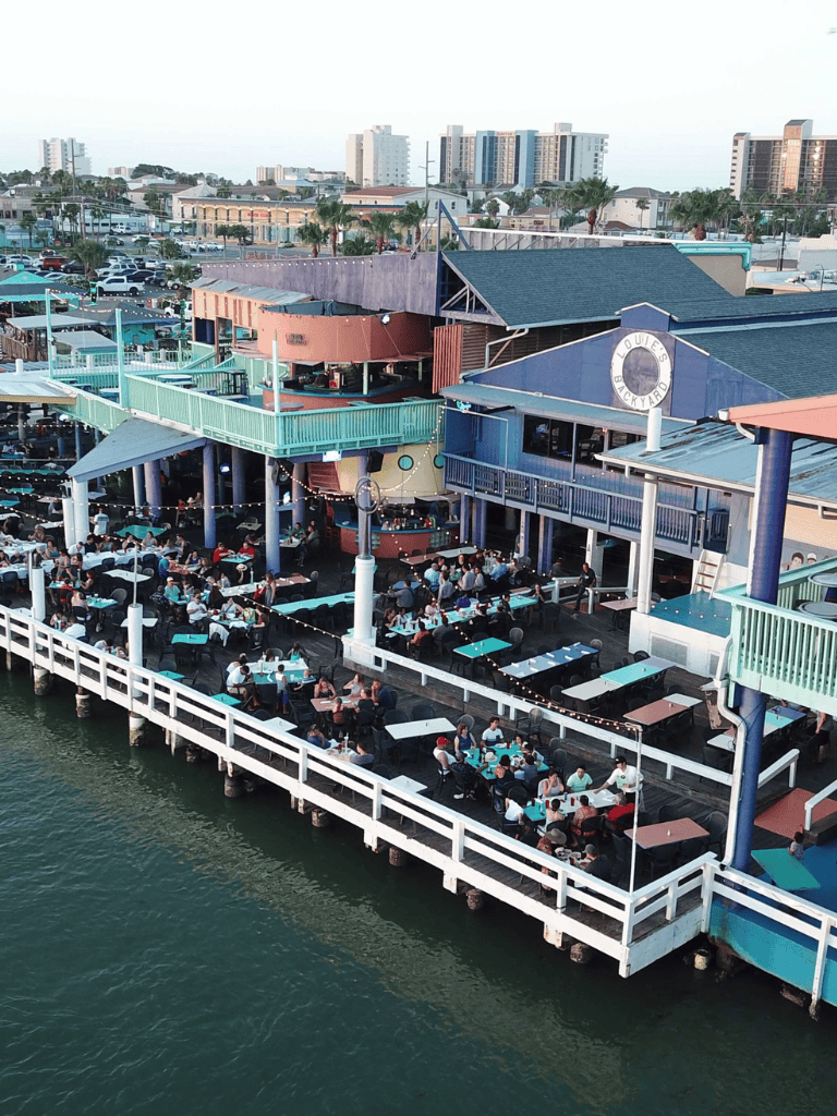 Outdoor waterfront dining at Quest For Directions restaurant, lively seating area with ocean view, popular for social gatherings and local cuisine.