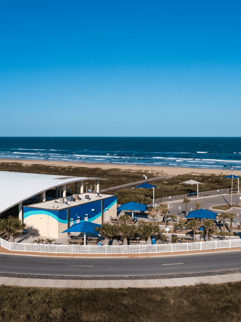 Beachside recreation center with ocean view and shaded seating areas, perfect for outdoor activities and relaxation.