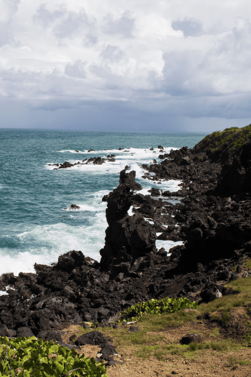 Stunning coastal scenery with rugged volcanic rocks and ocean waves for adventure travel.