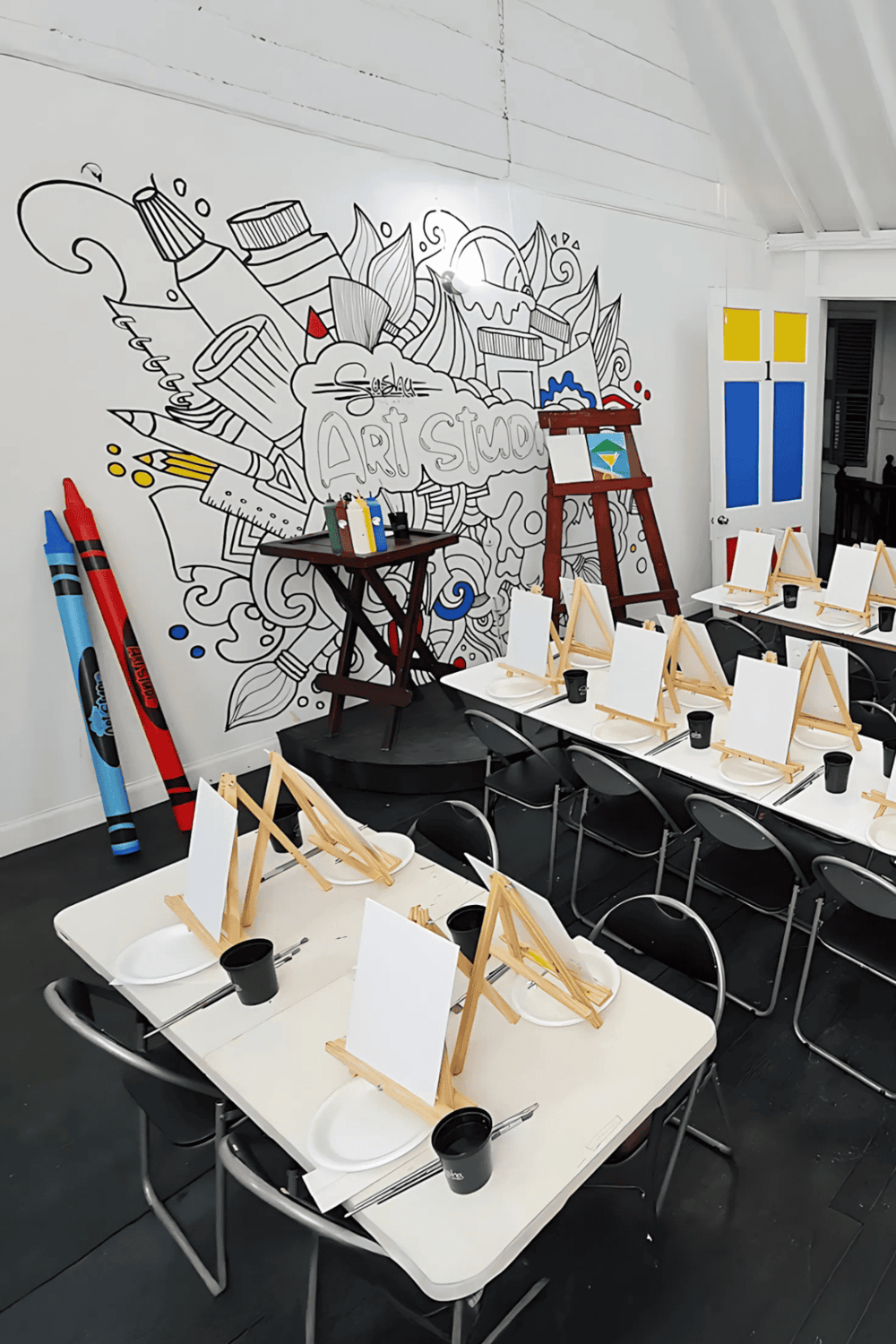 Creative art studio space with easels and mural wall, ideal for art & design workshops.