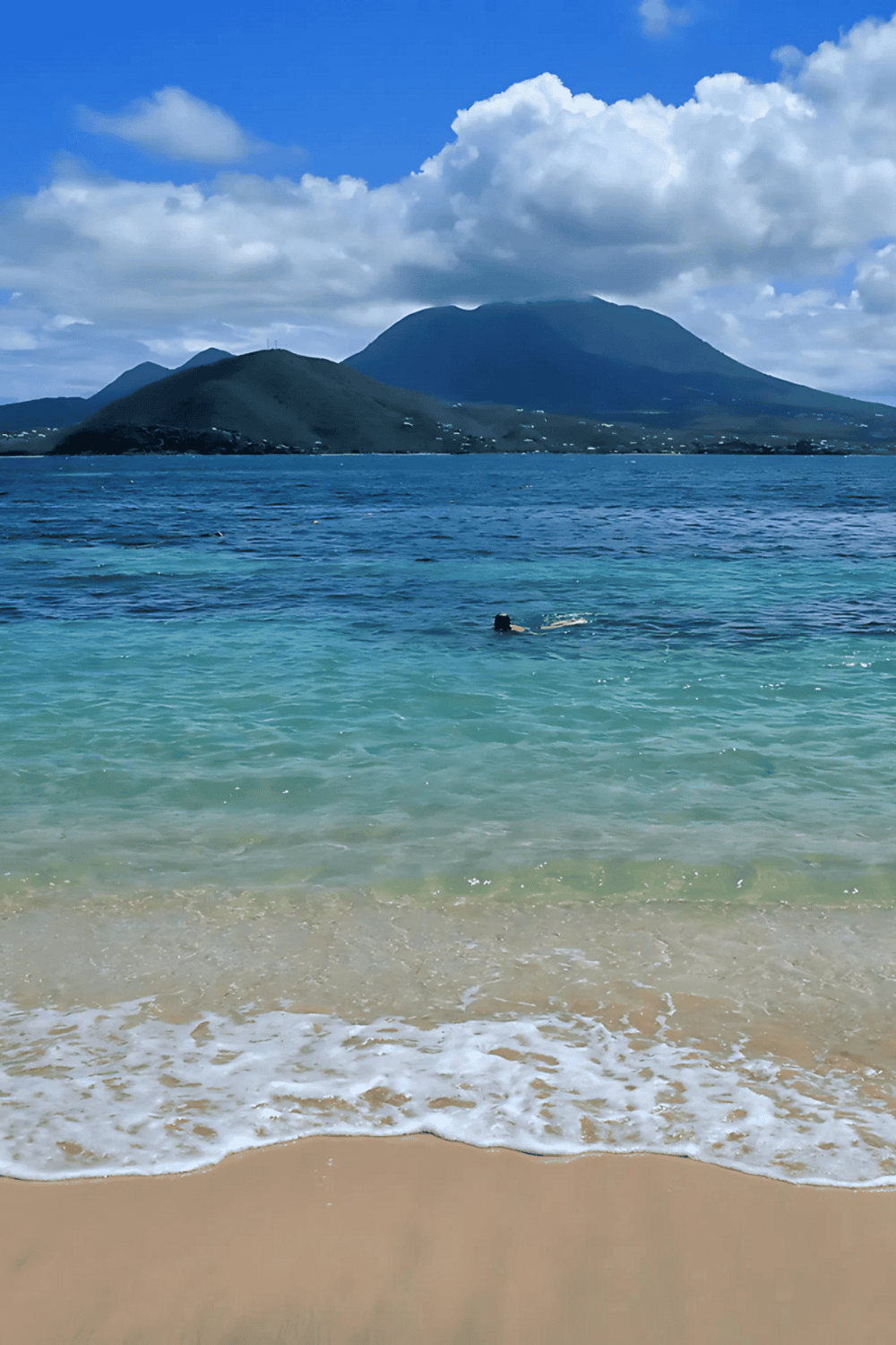 Azure ocean landscape with mountains and swimmer, Hawaii scenic view.
