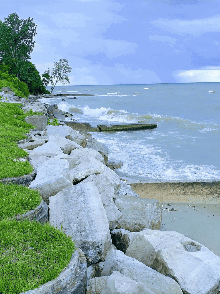 Tranquil lakeside scene with rocks, waves, and greenery, perfect for nature and outdoor activities.