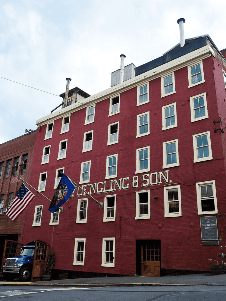 - Historic red brick building with "Yuengling & Son" signage and American flags.